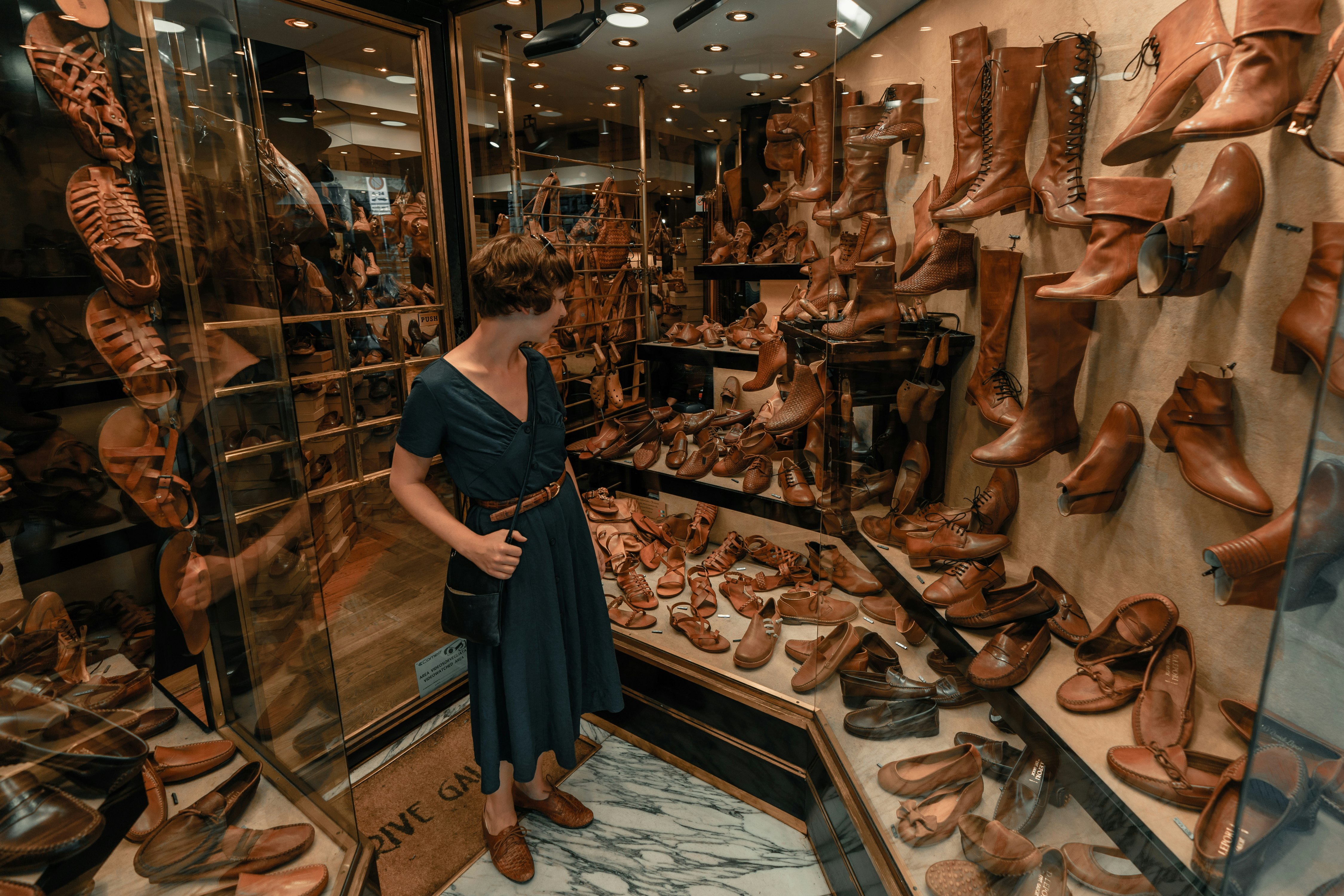 woman in black dress standing in front of brown leather shoes